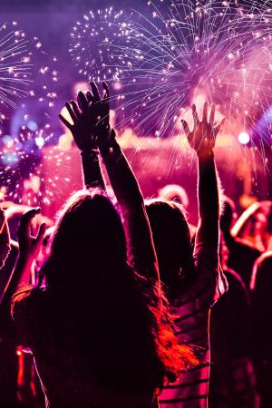 Cheering crowd with fireworks and music.