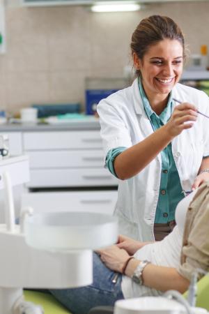 Dentista sorridente cura paziente in studio moderno.