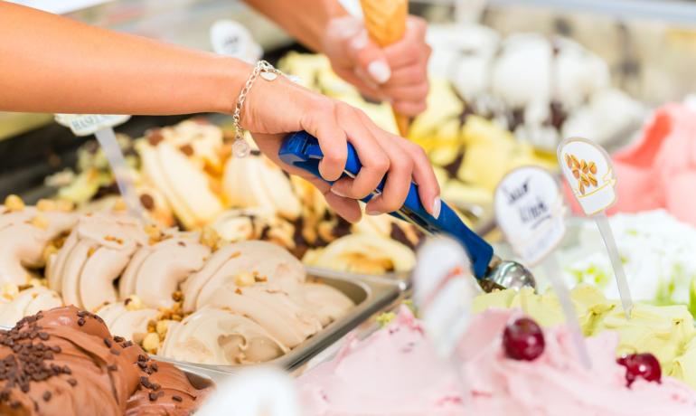 Glace artisanale servie dans un magasin, plusieurs saveurs disponibles.