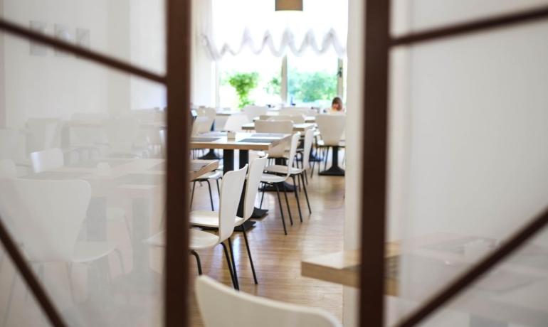 Ristorante vuoto con sedie bianche e tavoli in legno.