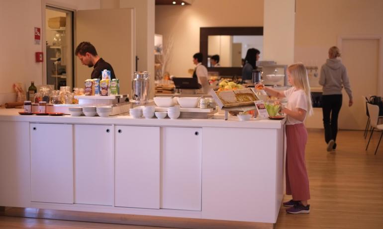 Buffet con cereali, latte e miele in una sala colazioni.